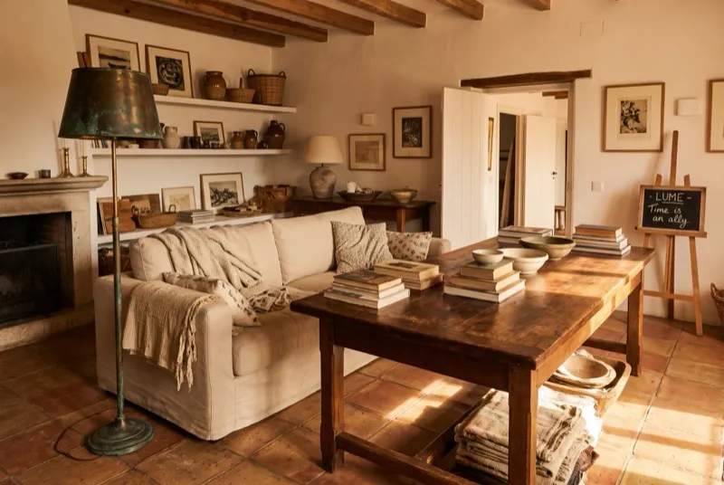 Sala com pátina bonita: mesa de carvalho com tom aquecido pelo uso, sofá de linho amaciado e latão com profundidade