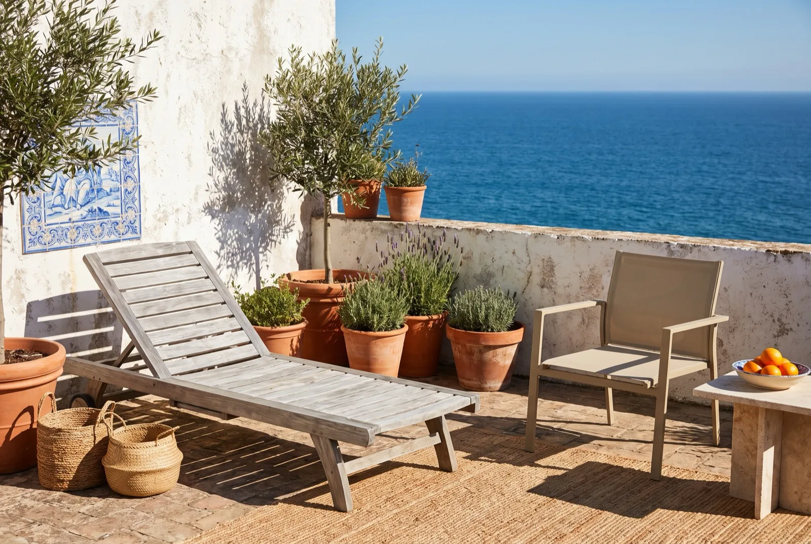 Mobiliário de exterior em teca e alumínio num terraço português ao sol, com patine natural