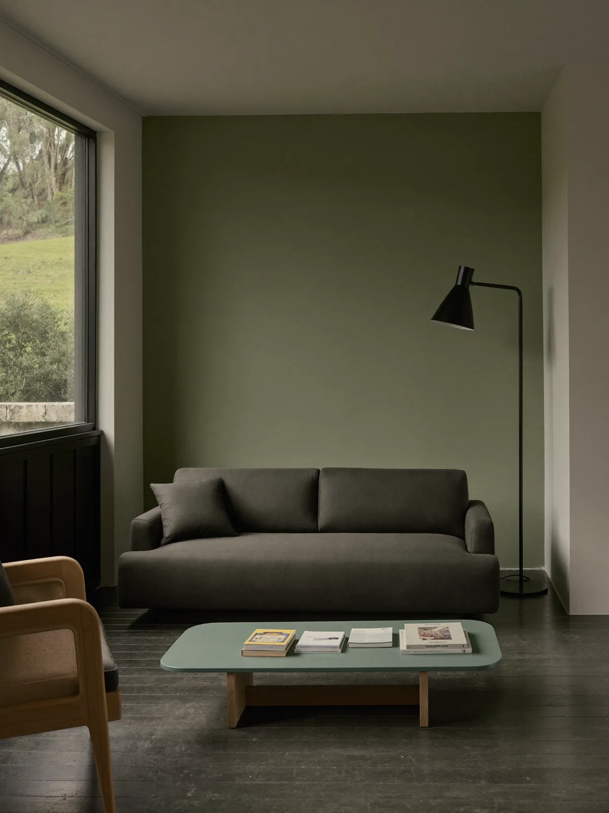 Sala minimalista em estilo arquivo: sofá de linhas limpas em carvão, candeeiro de pé em metal preto e muito espaço para respirar
