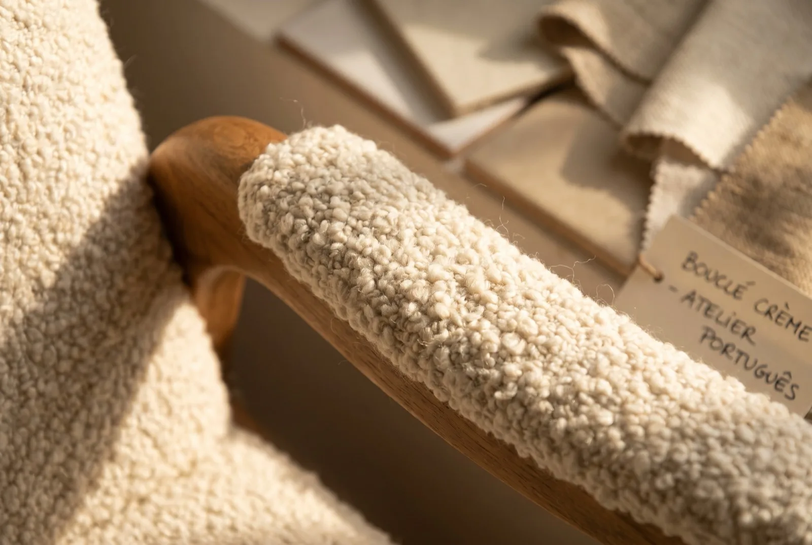 Textura de bouclé cru em grande plano, laçadas de fio visíveis sobre o braço de uma poltrona